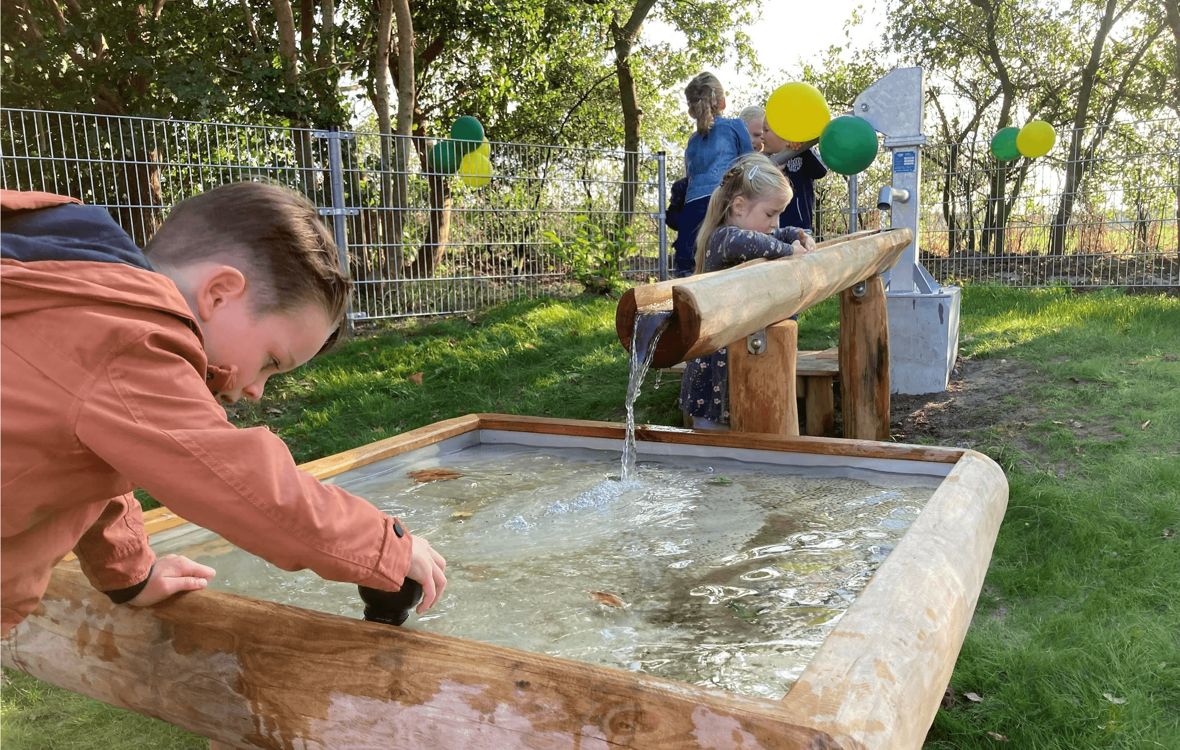 Kinderen spelen met een waterbak, er zijn ook ballonen
