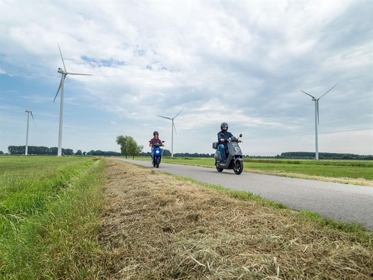 Mensen op scooter rijden langs windmolens