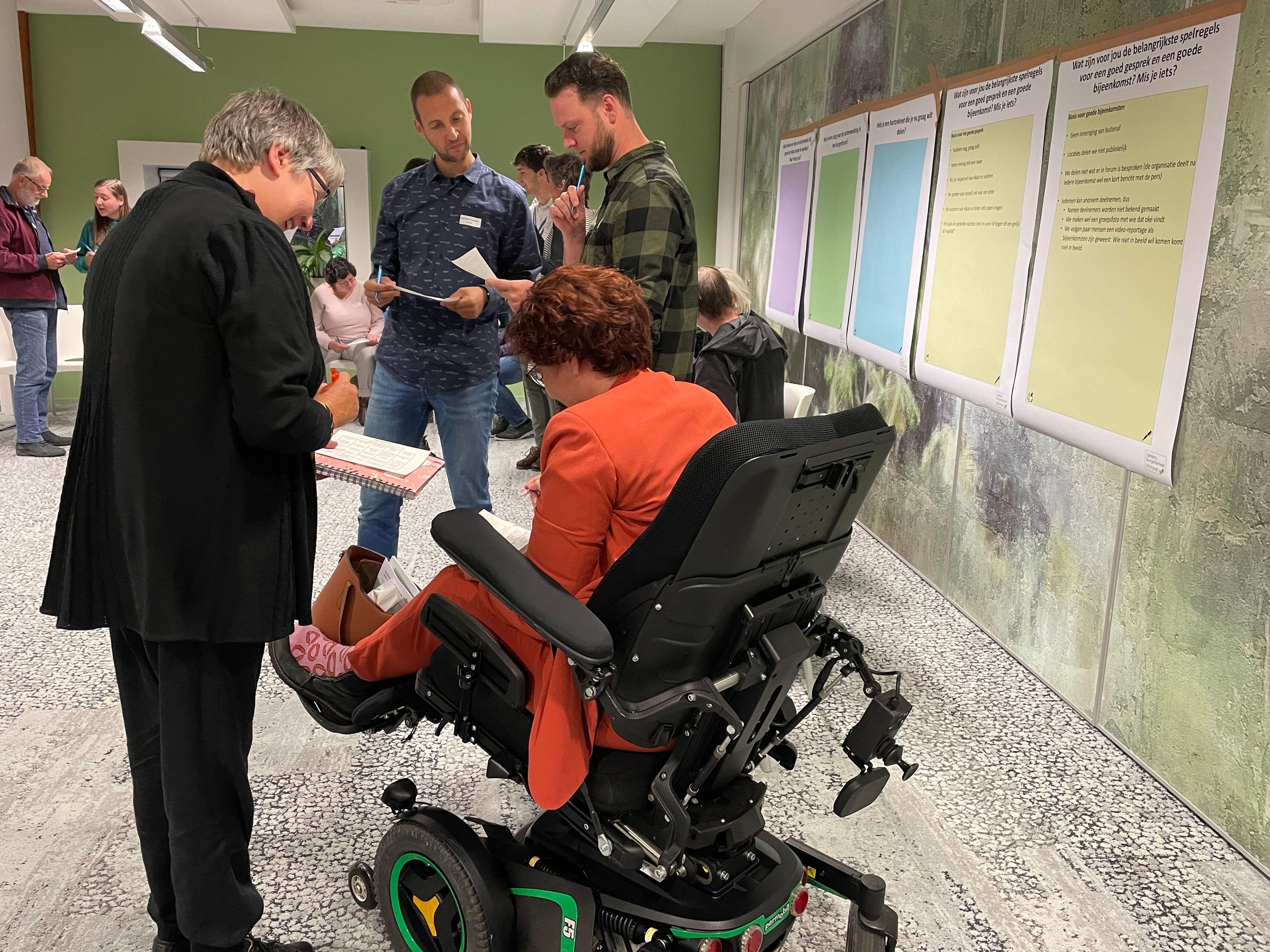 Deelnemer burgerberaad in aangepaste rolstoel in gesprek met mededeelnemer 