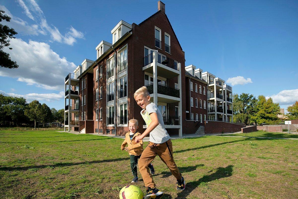 Twee voetballende jongens voor een aantal woningen