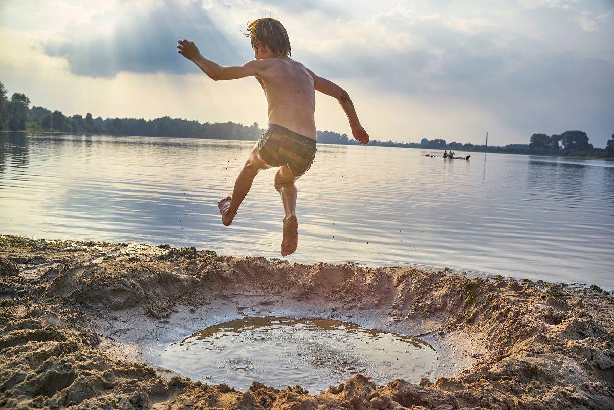 jongetje springt in natuurwaterplas