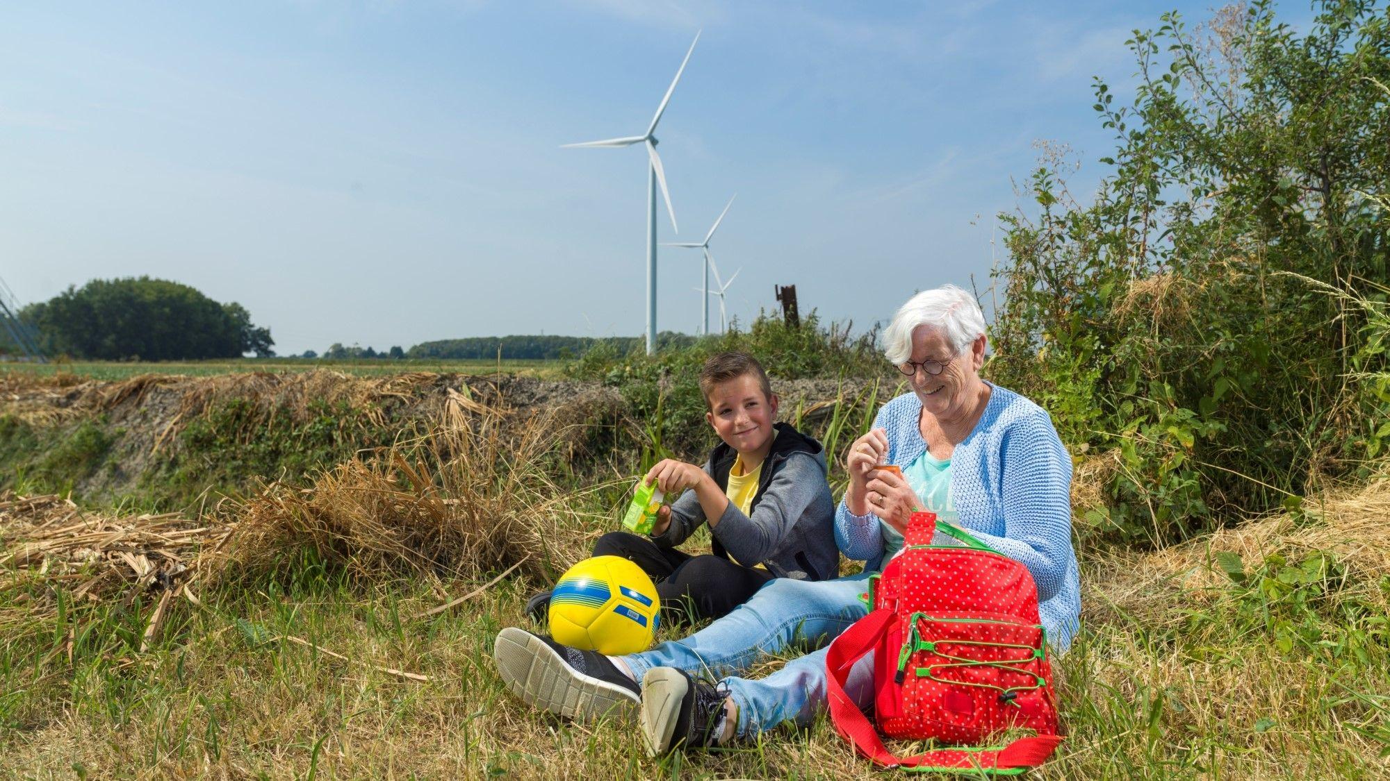 Oma met kleinkind in natuurpark met windmolens